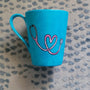 A Light blue mug with a stethoscope painted in pink