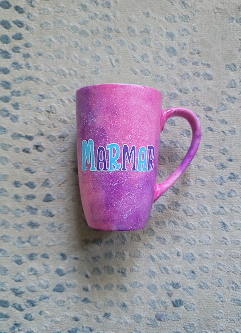 A hand painted pink galaxy mug with the name "marmar"