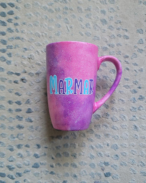 A hand painted pink galaxy mug with the name "marmar"