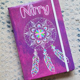 A Pink galaxy hand painted notebook with a dreamcatcher drawn in white and the name 