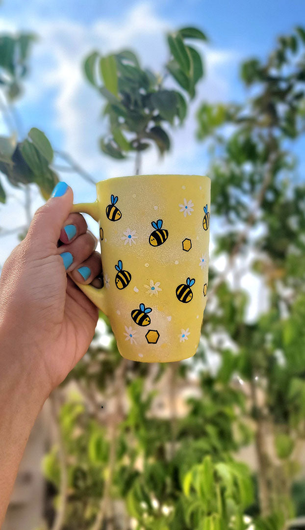 A Pastel yellow Hand painted mug with bees , white flowers and honey combs scattered all over