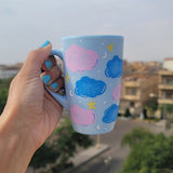 A Baby Blue Hand painted mug with colorful clouds (pink and blue) drawn all over with yellow stars