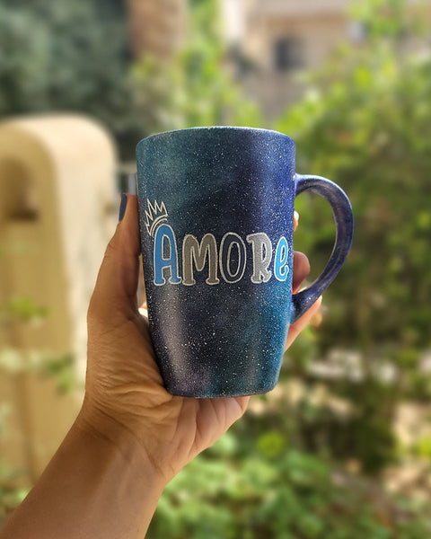 A black galaxy hand painted mug with the name "Amore" and a little crown on the letter A