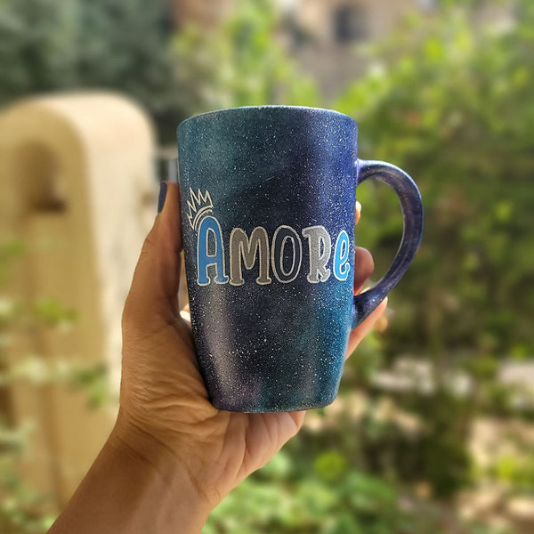 A black galaxy hand painted mug with the name "Amore" and a little crown on the letter A