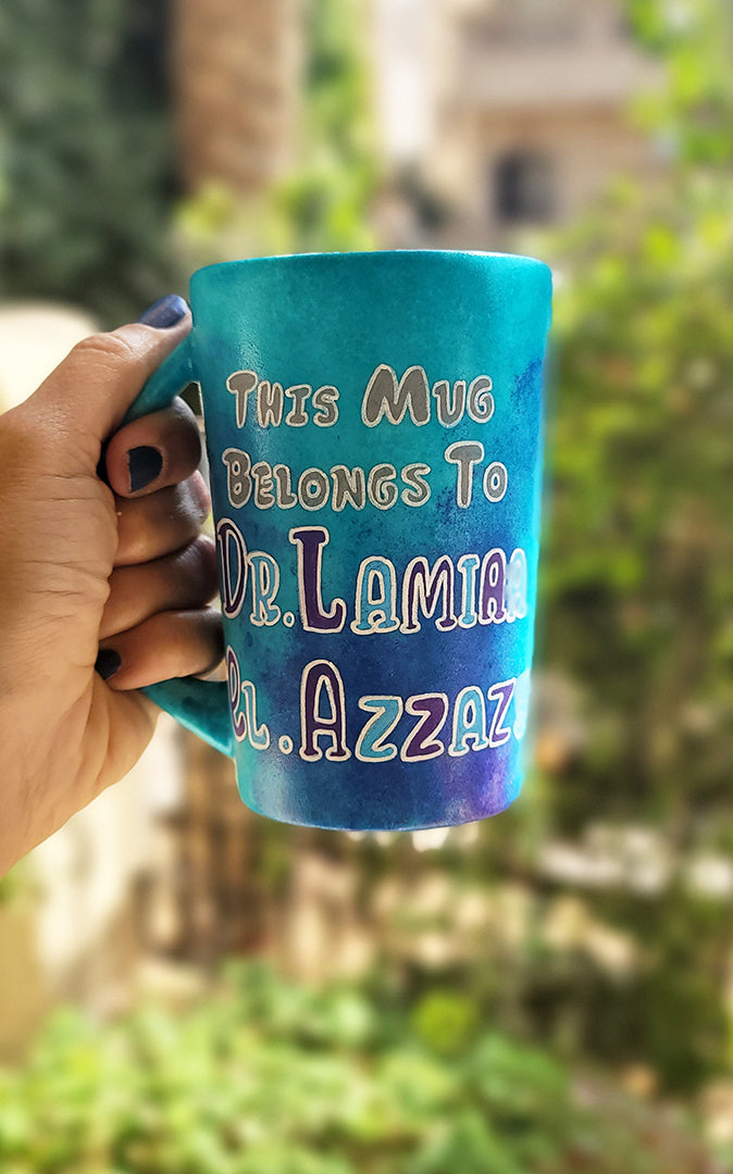 A Blue hand painted mug with the words :This mug belongs to Dr.Lamia el Azzazy"