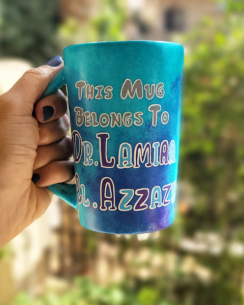 A Blue hand painted mug with the words :This mug belongs to Dr.Lamia el Azzazy"