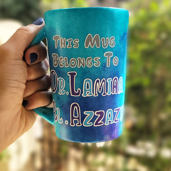 A Blue hand painted mug with the words :This mug belongs to Dr.Lamia el Azzazy"