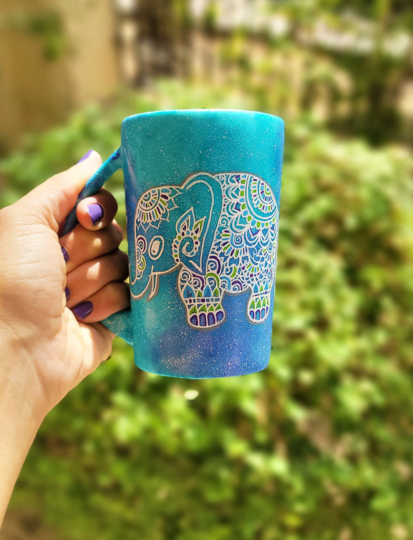 A Blue Galaxy hand painted mug with an elephant zentangle design on it in white