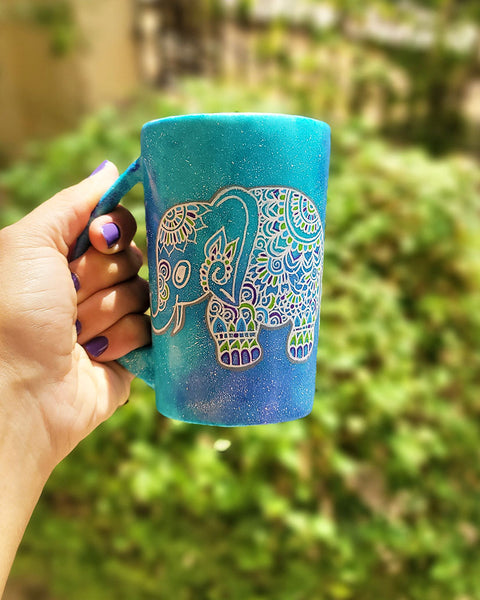 A Blue Galaxy hand painted mug with an elephant zentangle design on it in white