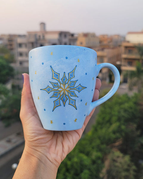 A baby blue hand painted mug with A snowflake in gold