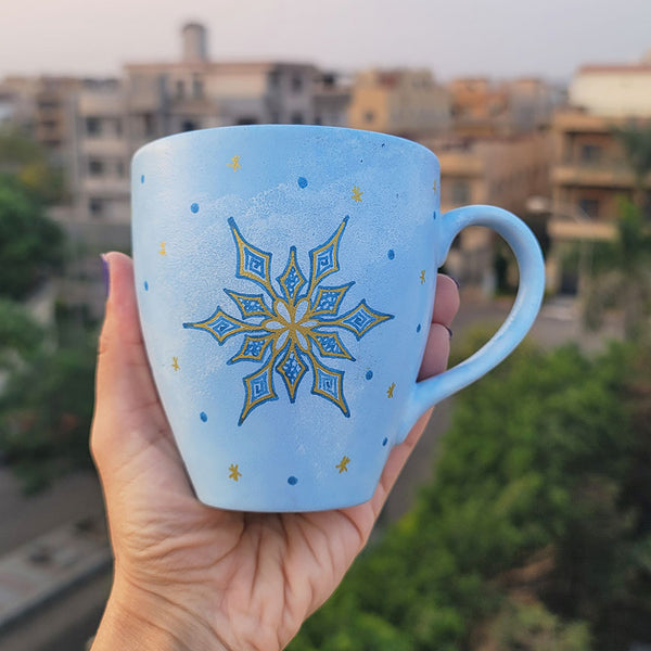 A baby blue hand painted mug with A snowflake in gold