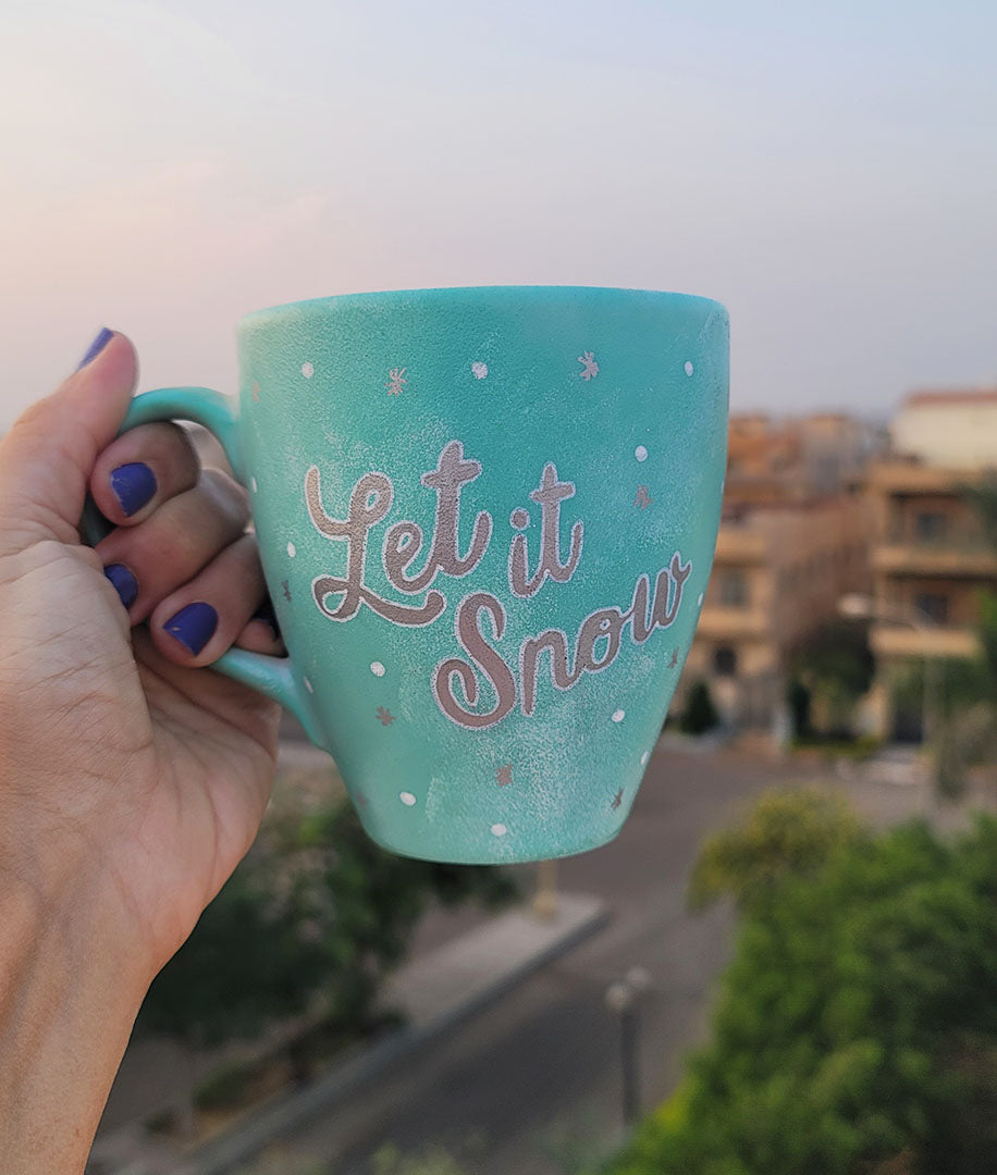 A Mint hand painted mug with the words "let it snow" in silver