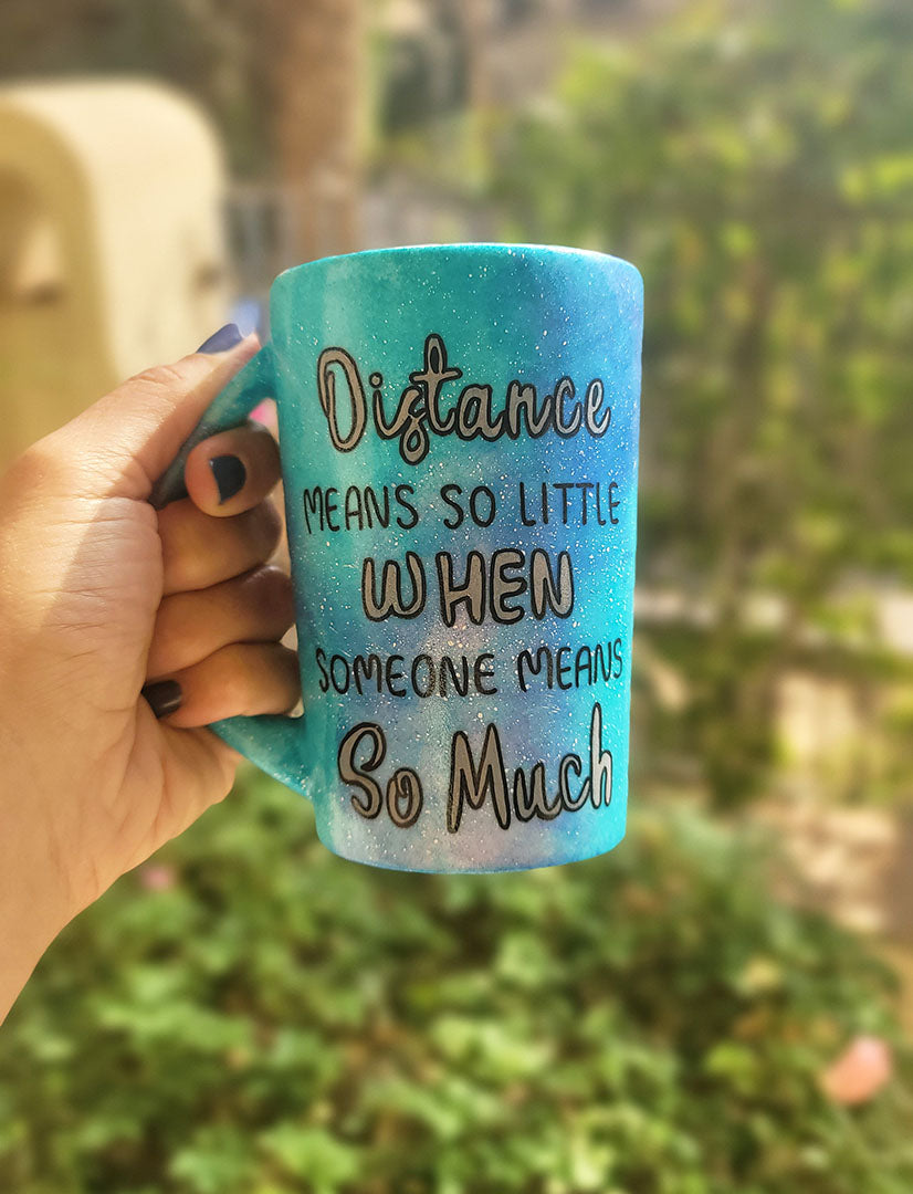 A Blue Galaxy hand painted mug with the words "Distance means so little "