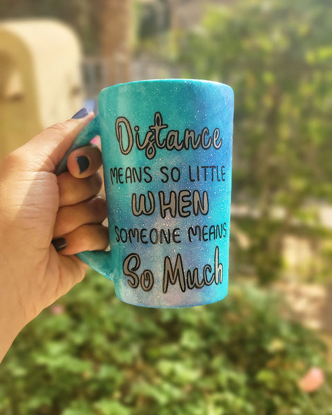 A Blue Galaxy hand painted mug with the words "Distance means so little "