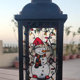 A Black Vintage Lantern with a snowman painted on the glass and festive lights above him