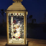 A White Vintage Lantern with a snowman painted on the glass and festive lights above him, shown at night when the lantern lights are on