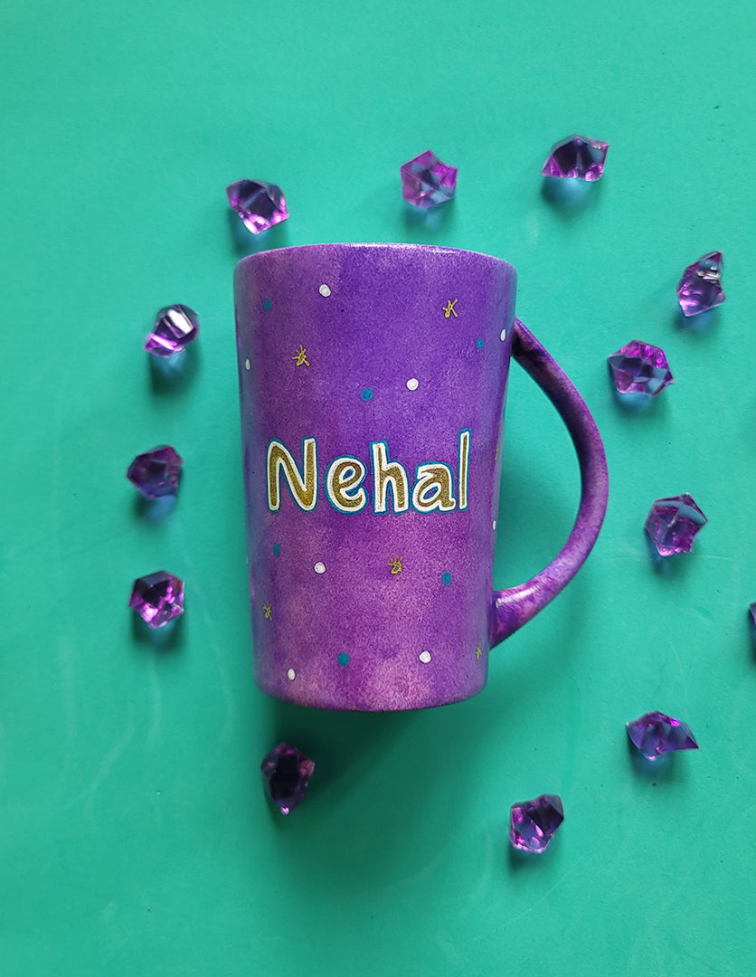 A Purple Hand painted mug with the name "Nehal" with turquoise gold and white dots scattered all over