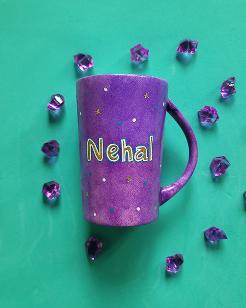 A Purple Hand painted mug with the name "Nehal" with turquoise gold and white dots scattered all over