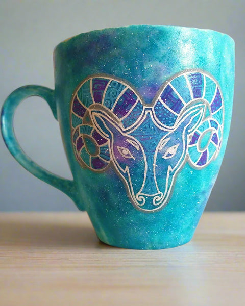 A Hand-painted blue galaxy mug with the Aries sign