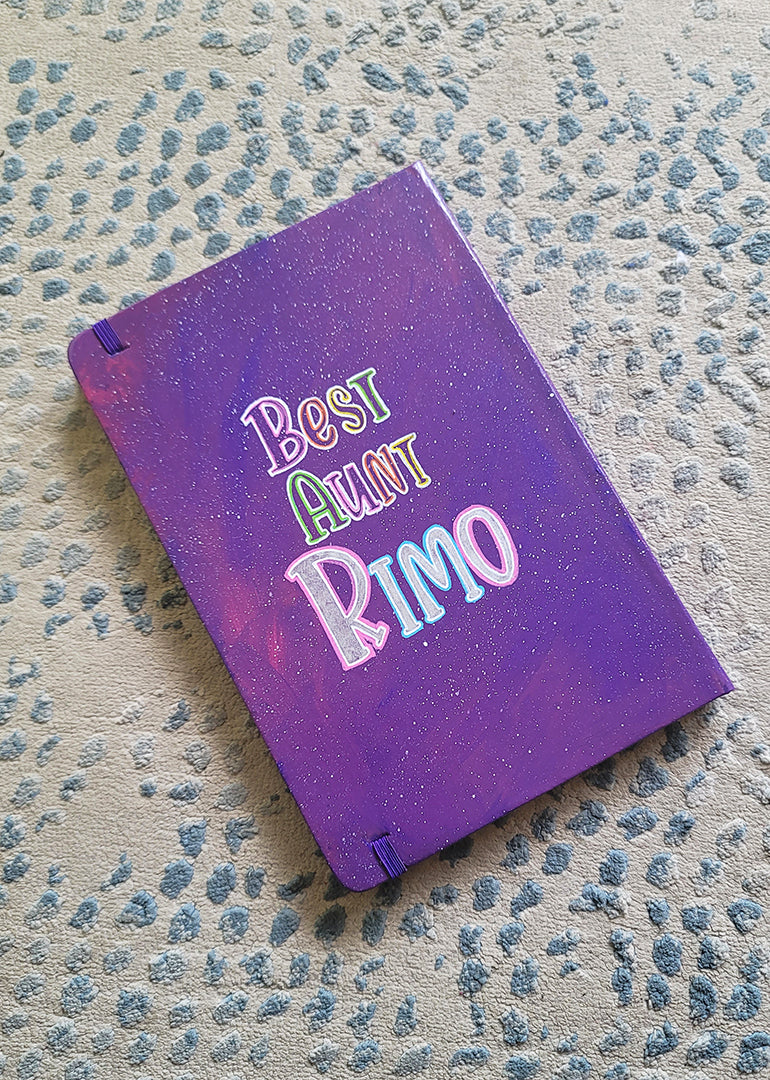 A Purple Galaxy Hand painted notebook with the words "Best Aunt Rimo"