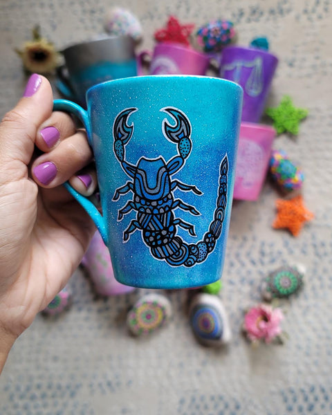 A blue galactic mug with a Scorpio zodiac sign hand-painted on it