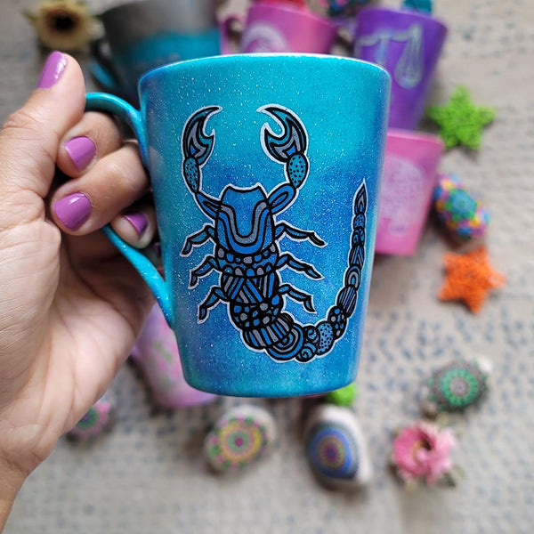 A blue galactic mug with a Scorpio zodiac sign hand-painted on it