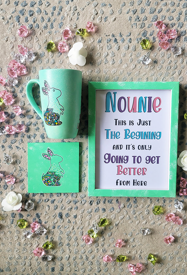 A Mint Green Hand painted gift set containing a mug with a a bunny design a matching coaster and a frame with the name "Nounie" and a quote.