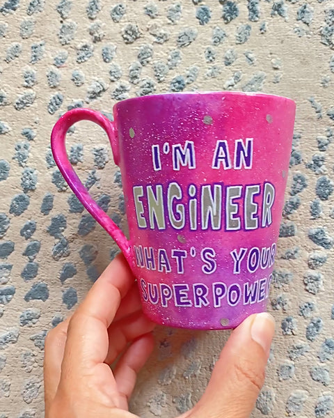 A Pink galaxy hand painted mug with the sentence "I'm and Engineer what your superpower"