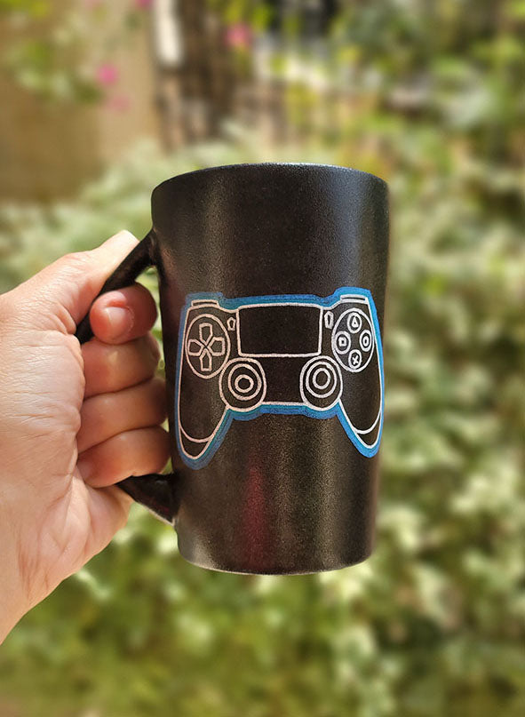 A Black sky mug with a joystick drawn on it