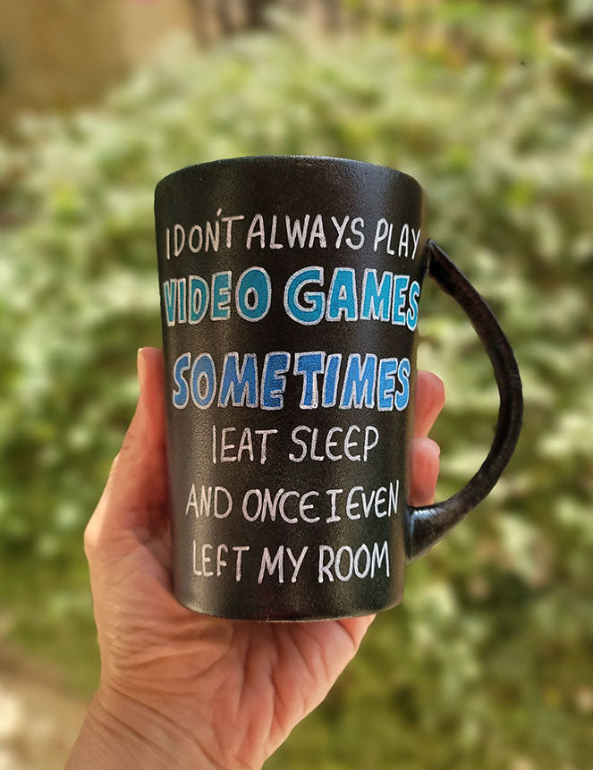 A Black sky hand painted mug with the sentence" I dont always play video games, sometimes I eat Sleep and once I even left my room"