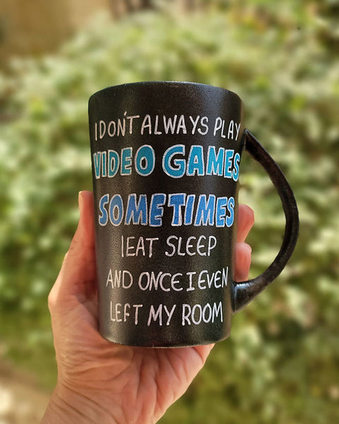 A Black sky hand painted mug with the sentence" I dont always play video games, sometimes I eat Sleep and once I even left my room"