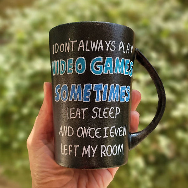 A Black sky hand painted mug with the sentence" I dont always play video games, sometimes I eat Sleep and once I even left my room"