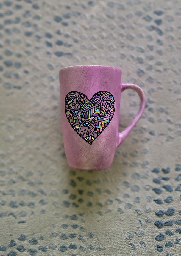 a Pastel Pink hand painted mug with a heart drawn in black filled with colorful patterns