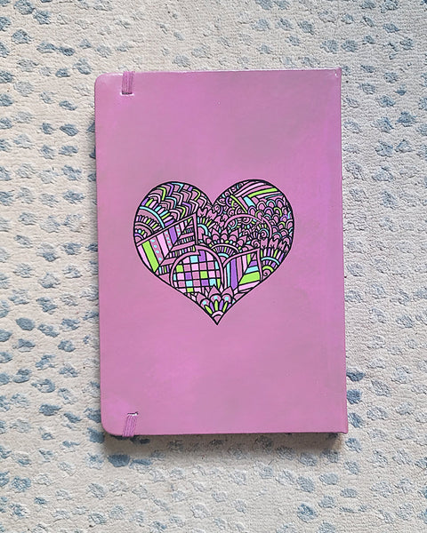 a Pastel Pink hand painted Notebook with a heart drawn in black filled with colorful patterns