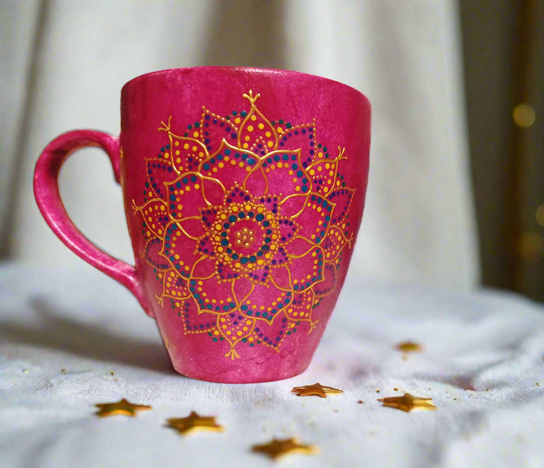 A hand painted pink Indian color mug with a mandala painted in gold