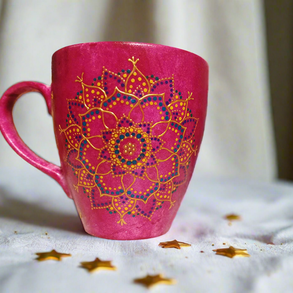 A hand painted pink Indian color mug with a mandala painted in gold