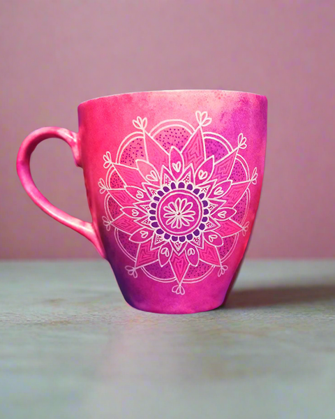 A Pink hand painted mug with a mandala drawn in white and colored in purple and pink