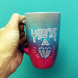 A Gradient colored mug(grey, blue and fushia) with the words 