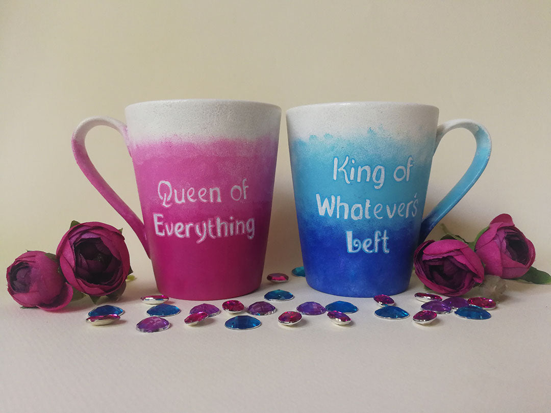 2 hand-painted mugs. One with gradients of pink and has the words "queen of everything" and the other is colored in gradients of blue and has the words "King of whatever's left"