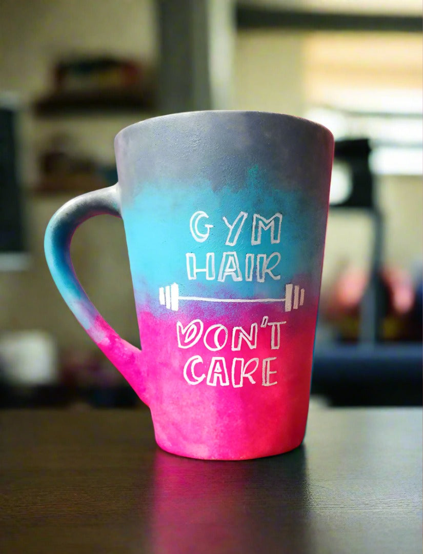 A gradient colored mug (from top grey then blue then pink) with the words "Gym hair, don't care" and a weight bar in between