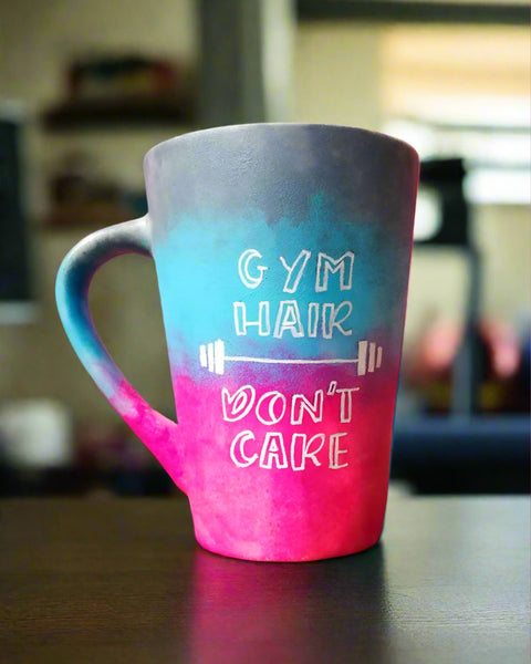 A gradient colored mug (from top grey then blue then pink) with the words "Gym hair, don't care" and a weight bar in between