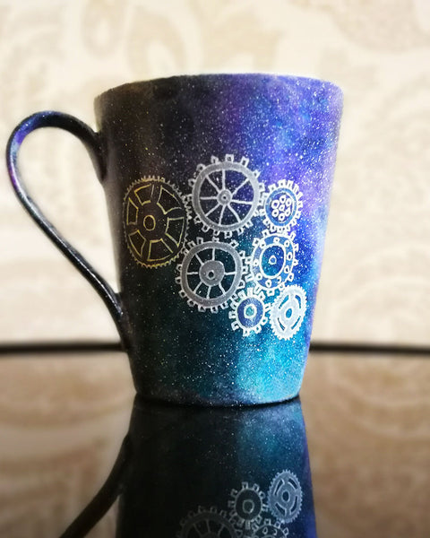 A Bluish Galaxy mug with gears painted on it in grey