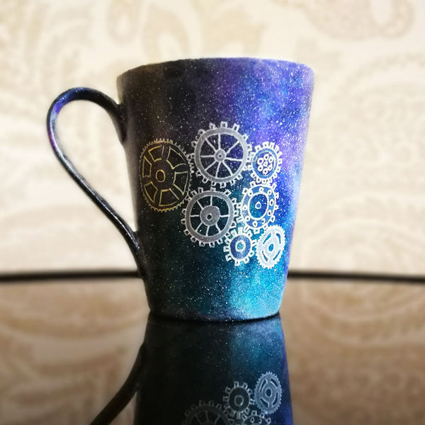 A Bluish Galaxy mug with gears painted on it in grey