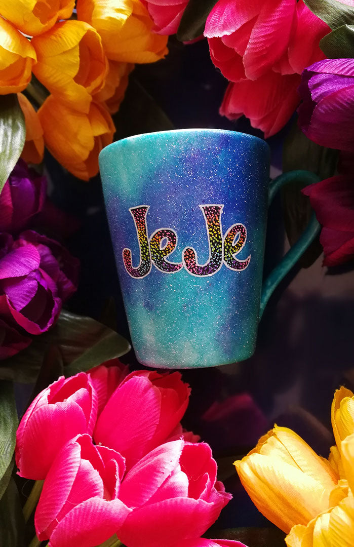 A Blue galaxy hand painted mug with the name "JeJe" painted in black and colorful dots on top, outline with white