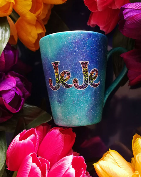 A Blue galaxy hand painted mug with the name "JeJe" painted in black and colorful dots on top, outline with white