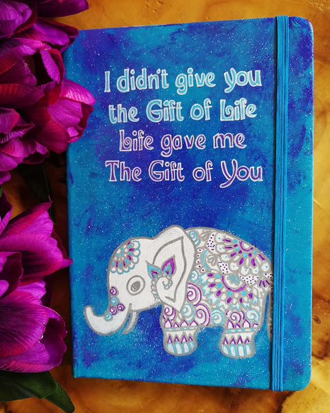 A Blue hand painted notebook with the words "I didnt give you the fit of life, Life gave me the gift of you" and a n elephant drawn below it in white and filled with patterns