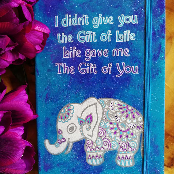 A Blue hand painted notebook with the words "I didnt give you the fit of life, Life gave me the gift of you" and a n elephant drawn below it in white and filled with patterns