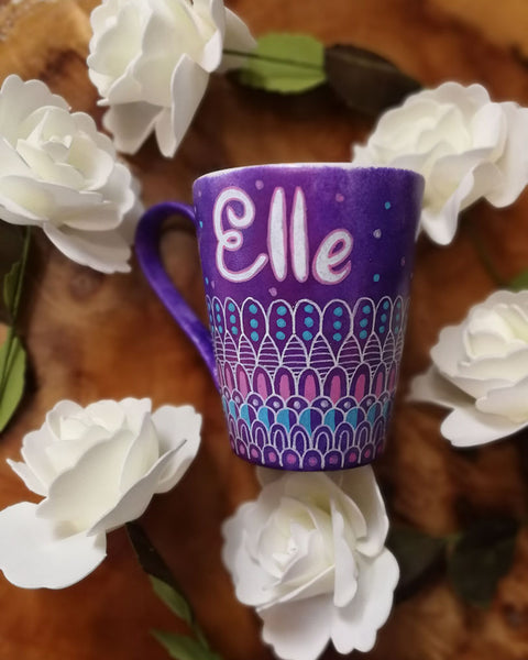 A Purple hand painted mug with patterns on the bottom half horizontally in white and colored in pink and blue with the name "Elle" on the top