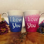 2 hand-painted mugs. one colored in gradient blues to white and has the words I love you on it. the other is colored in gradient pinks to white and has the words I love you on it