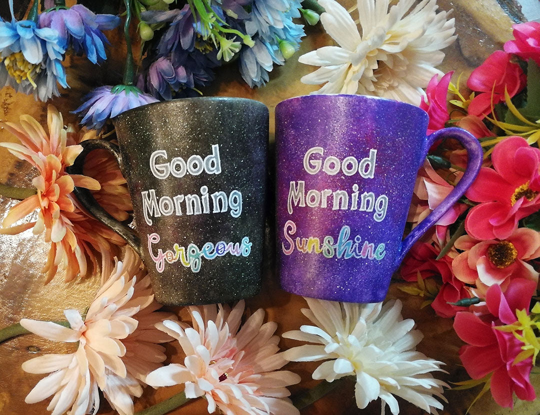 two hand-painted mugs, one in purple galaxy color  and the words "good morning sunshine" and the other in black galaxy color with the words "good morning gorgeous"